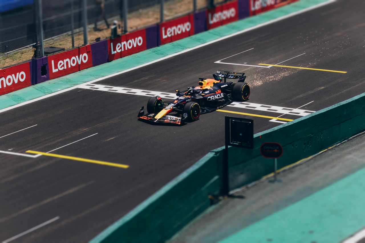 about-img Formula 1 car speeding across the finish line on a racetrack, emitting sparks.