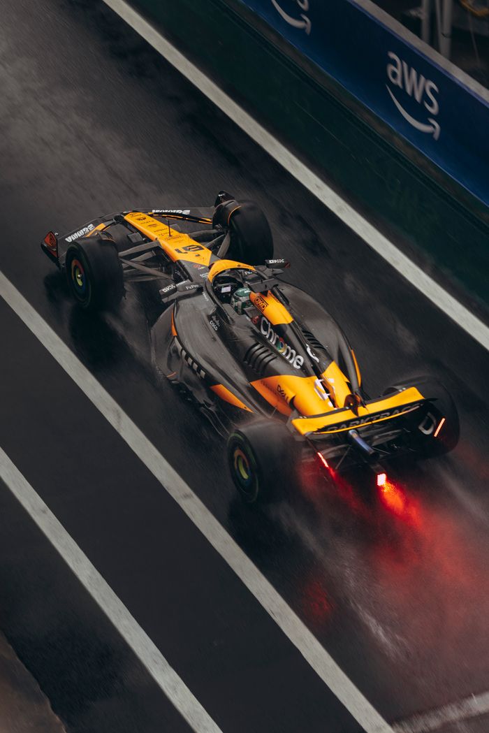 Exciting action shot of a Formula One car speeding on a rain-soaked track with vibrant lighting.