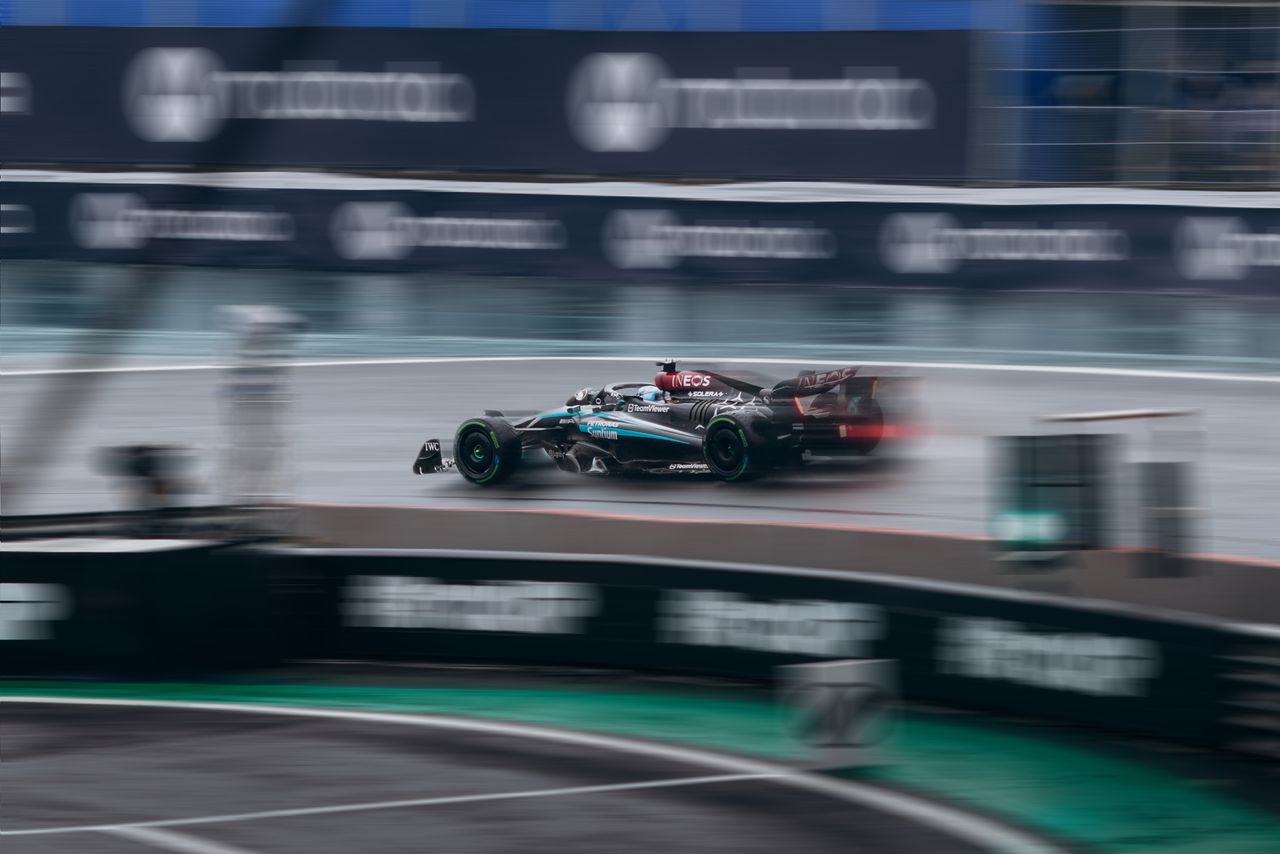 Dynamic shot of a racing car speeding during a Formula 1 event on a wet track.